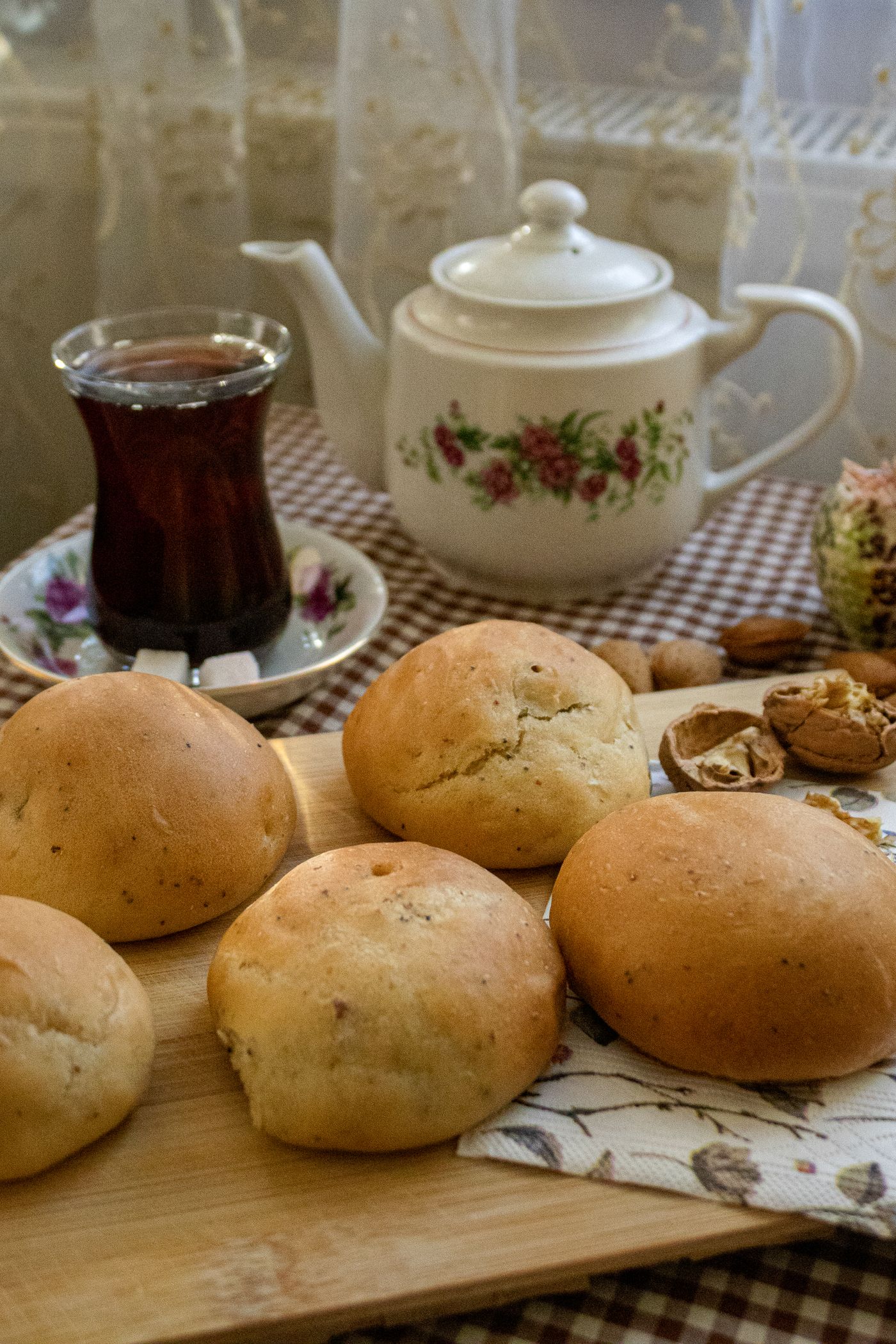 An afternoon tea setting with a floral teapot and fresh buns