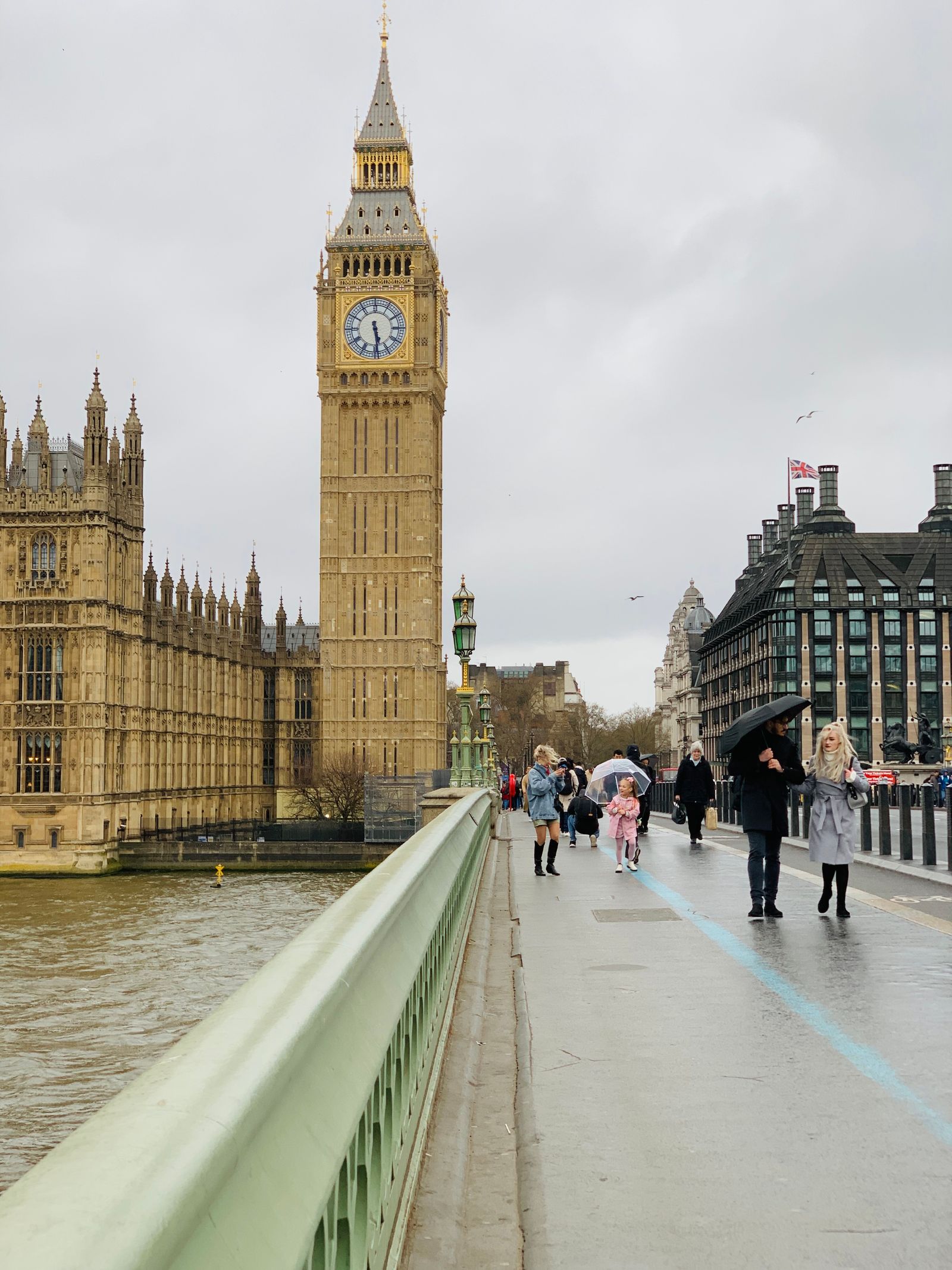 People walking under umbrellas on Westminster Bridge towards Big Ben