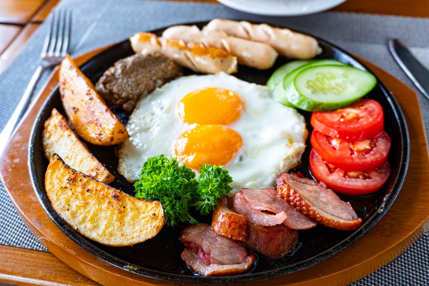 A full English breakfast with eggs, bacon, sausage and beans on a plate