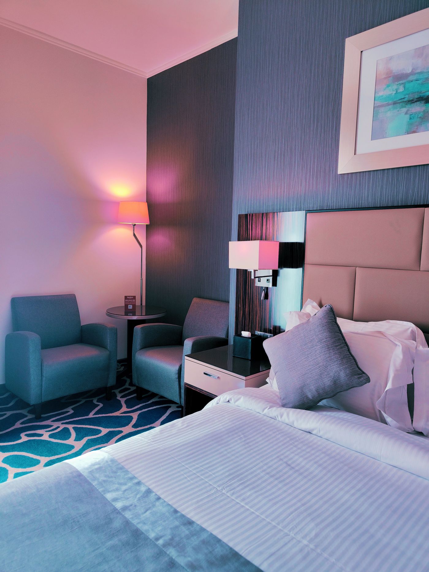 A softly lit hotel room with modern lamps and bedside table