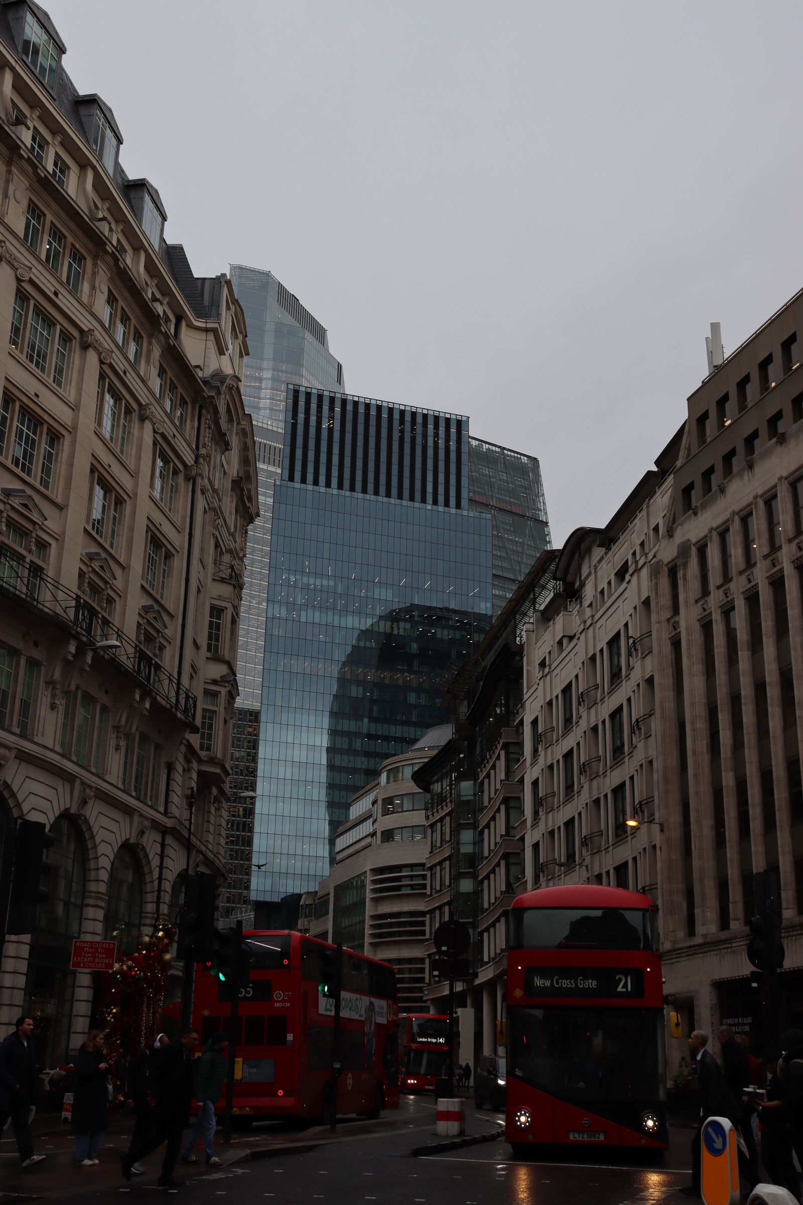 Red double-decker buses on a busy London street with modern towers behind