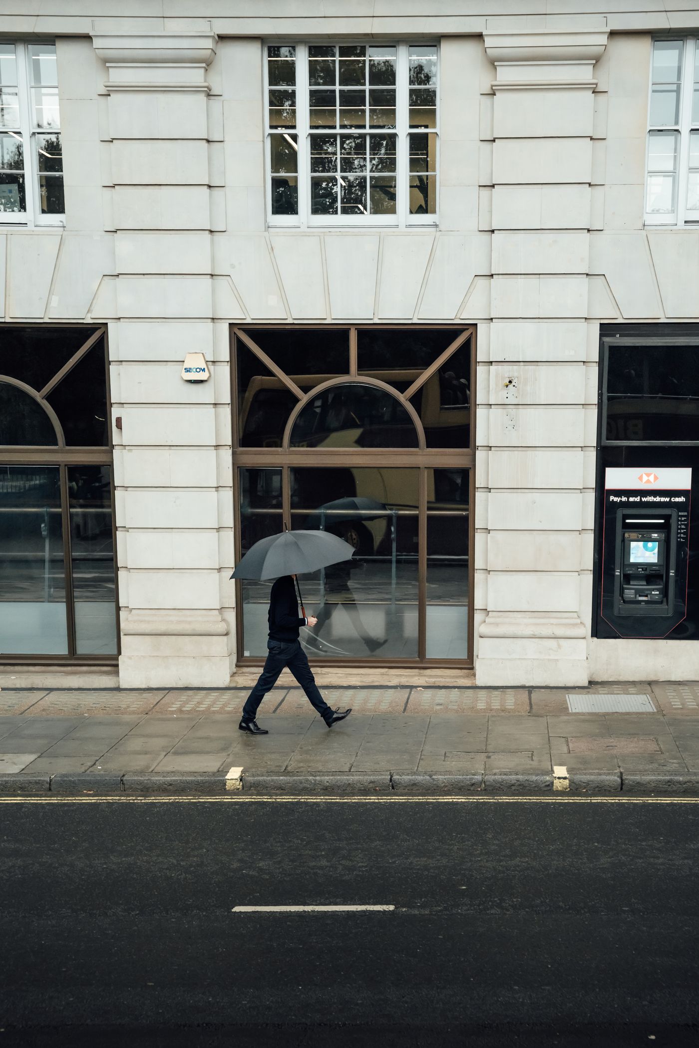 A person holding an umbrella walking through heavy rain on a city street