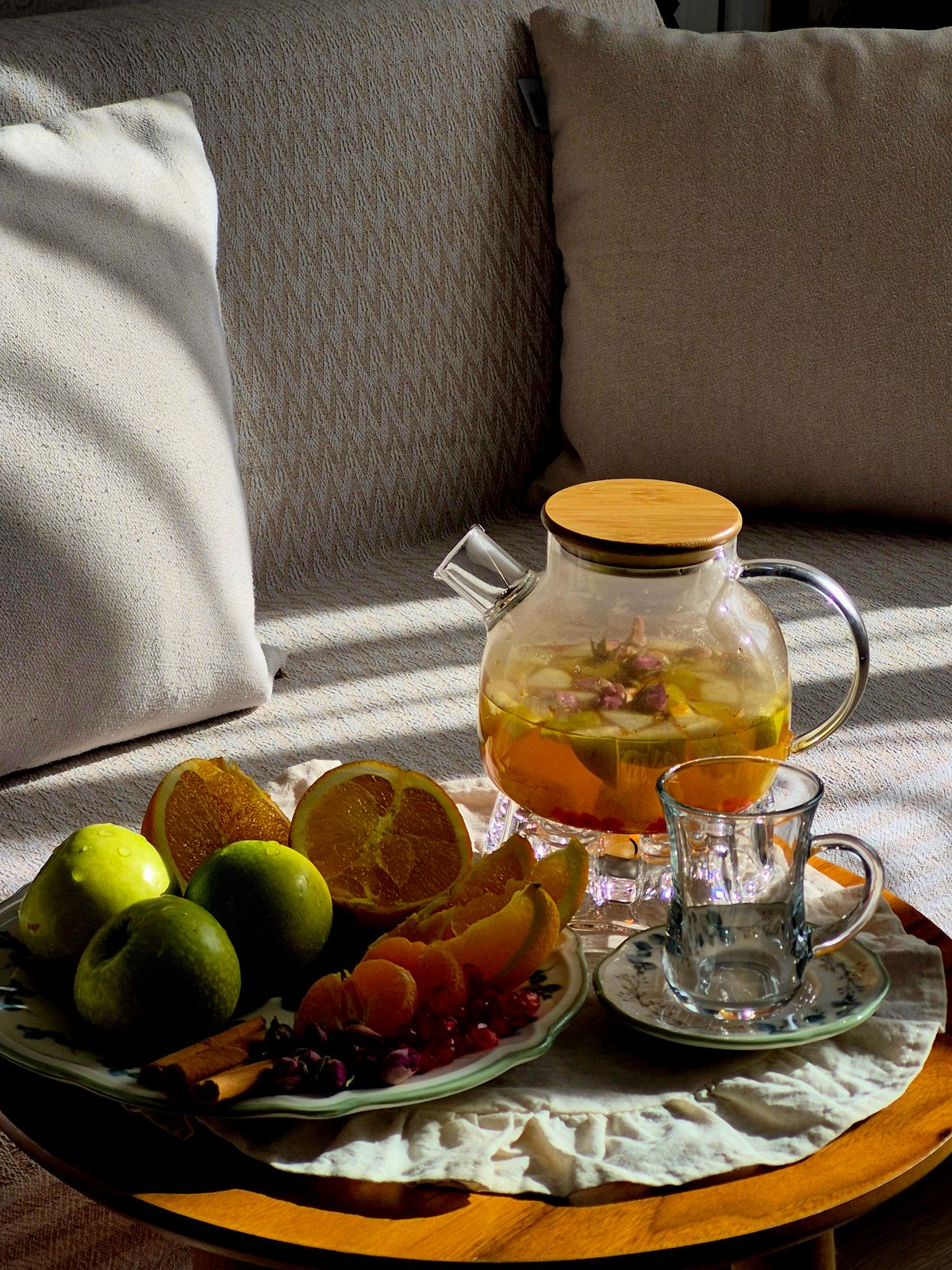 A cup of herbal tea beside a small teapot on a table