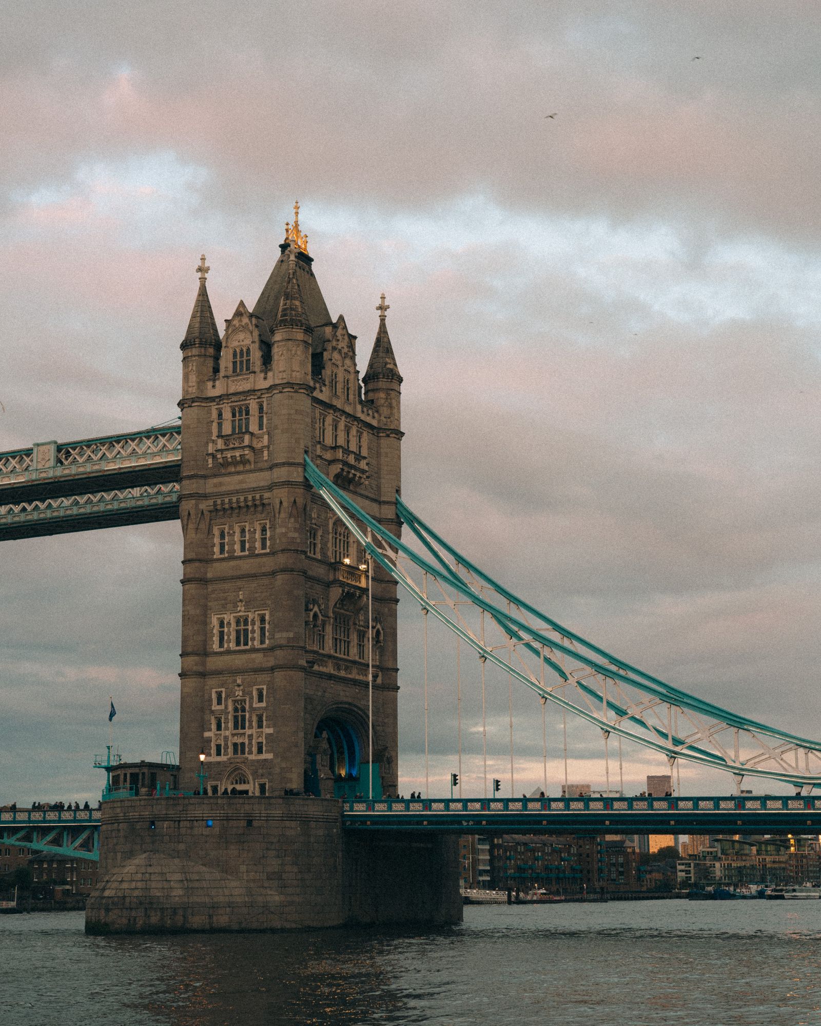 Tower Bridge illuminated at dusk with the River Thames in the foreground
