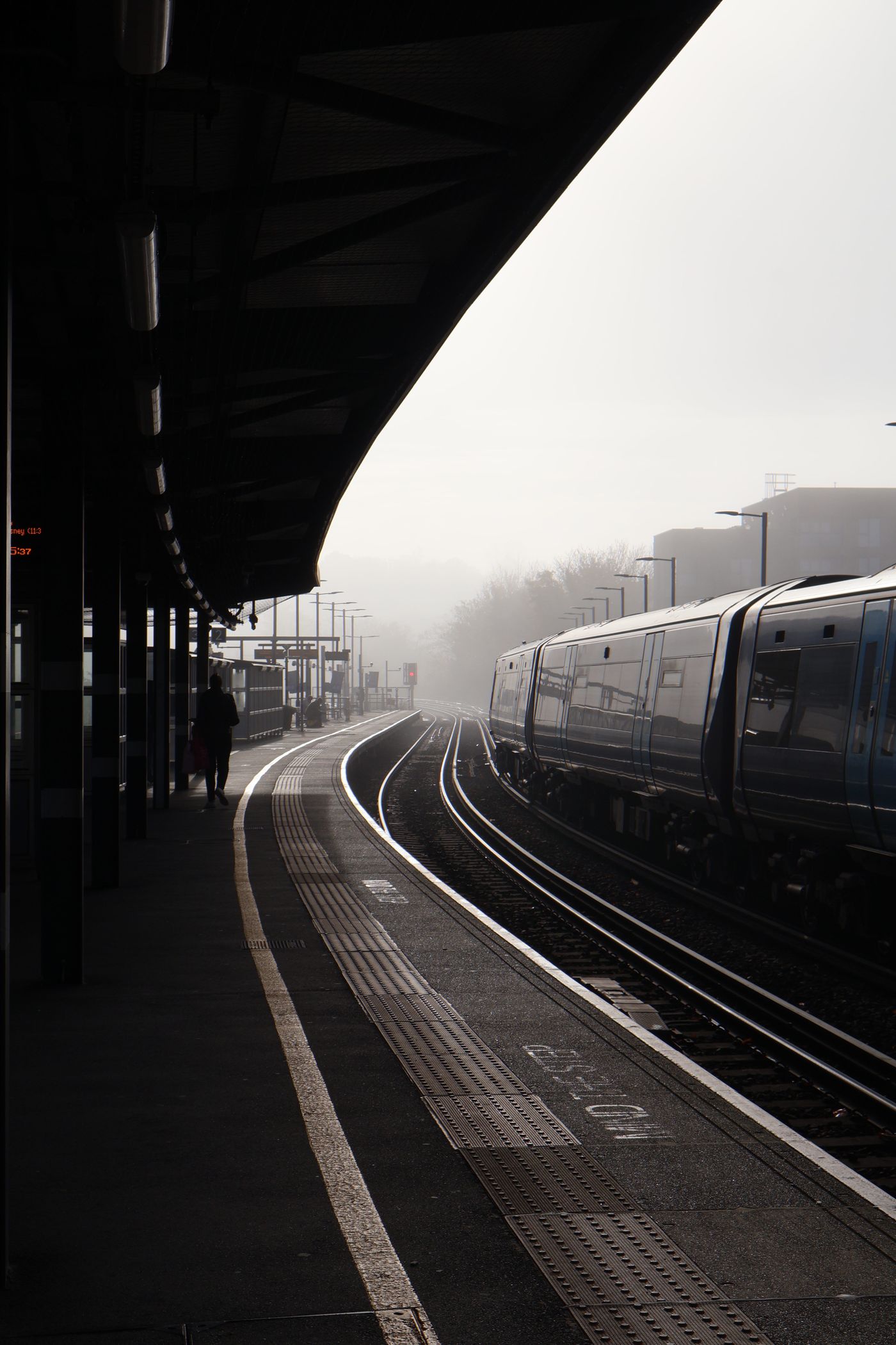 A train emerging through fog on a rural railway line
